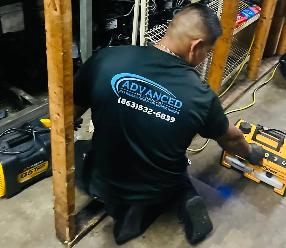 Advanced Mechanical technician in a company shirt running a refrigerant recovery machine